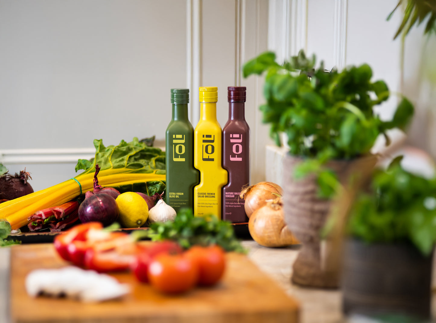 FOLI essentials bundle bottles on a kitchen counter with fresh vegetables and herbs.