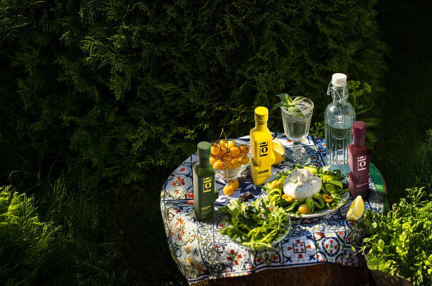 Table outdoors with FOLI essentials kit drinks, fruits, and a bottle of still water