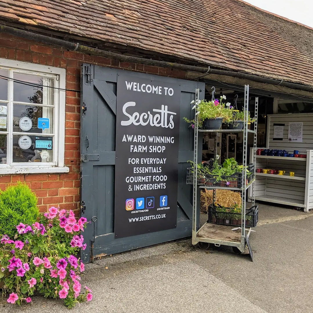 Secrets farm shop entrance with a sign welcoming customers.