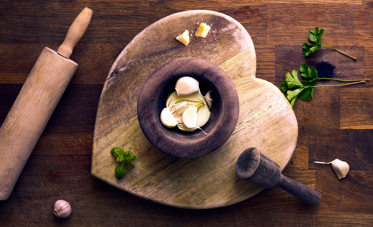 Wooden mortar and pestle with garlic on a wooden surface