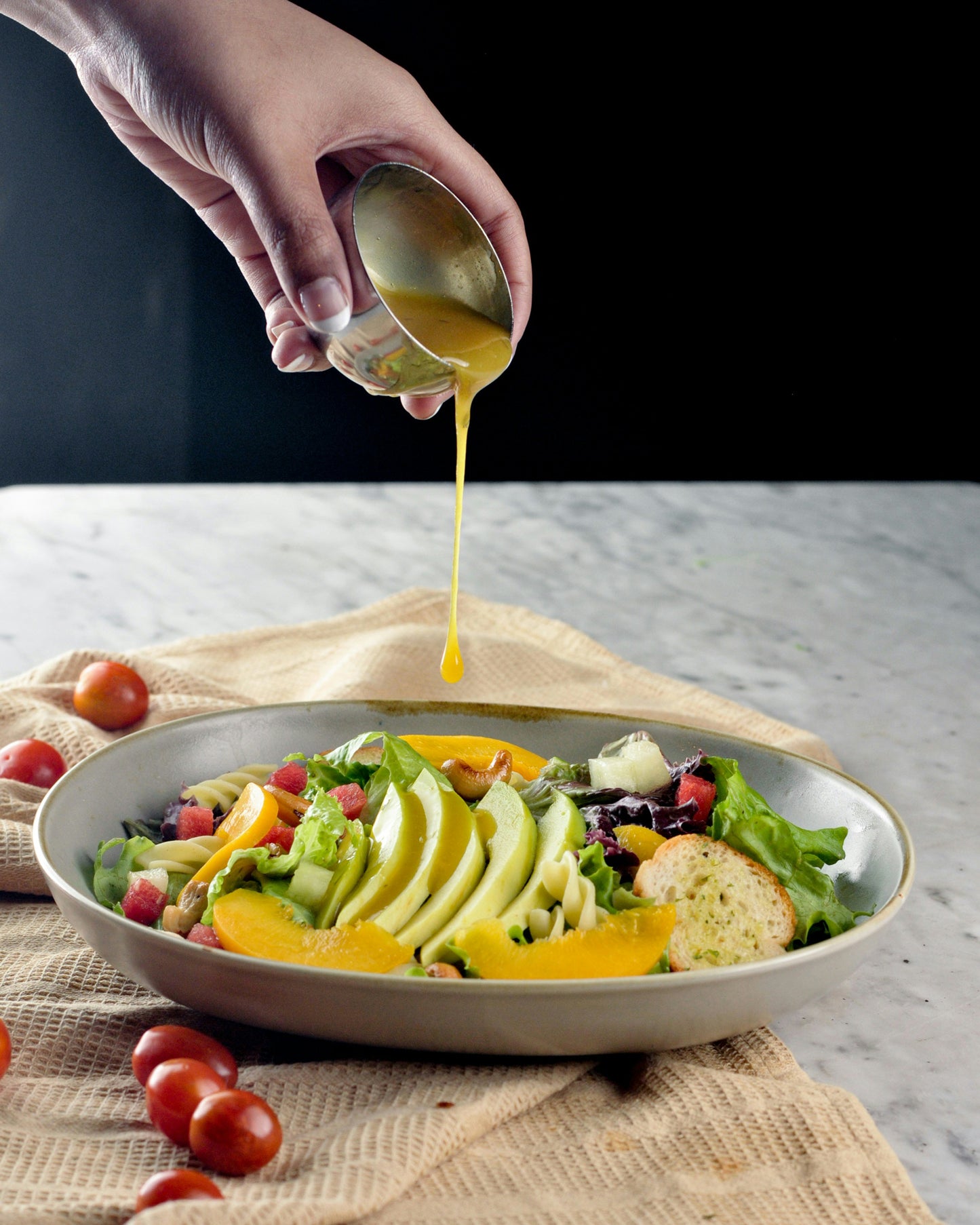 fresh salad with salad dressing being poured from a height from a small bowl